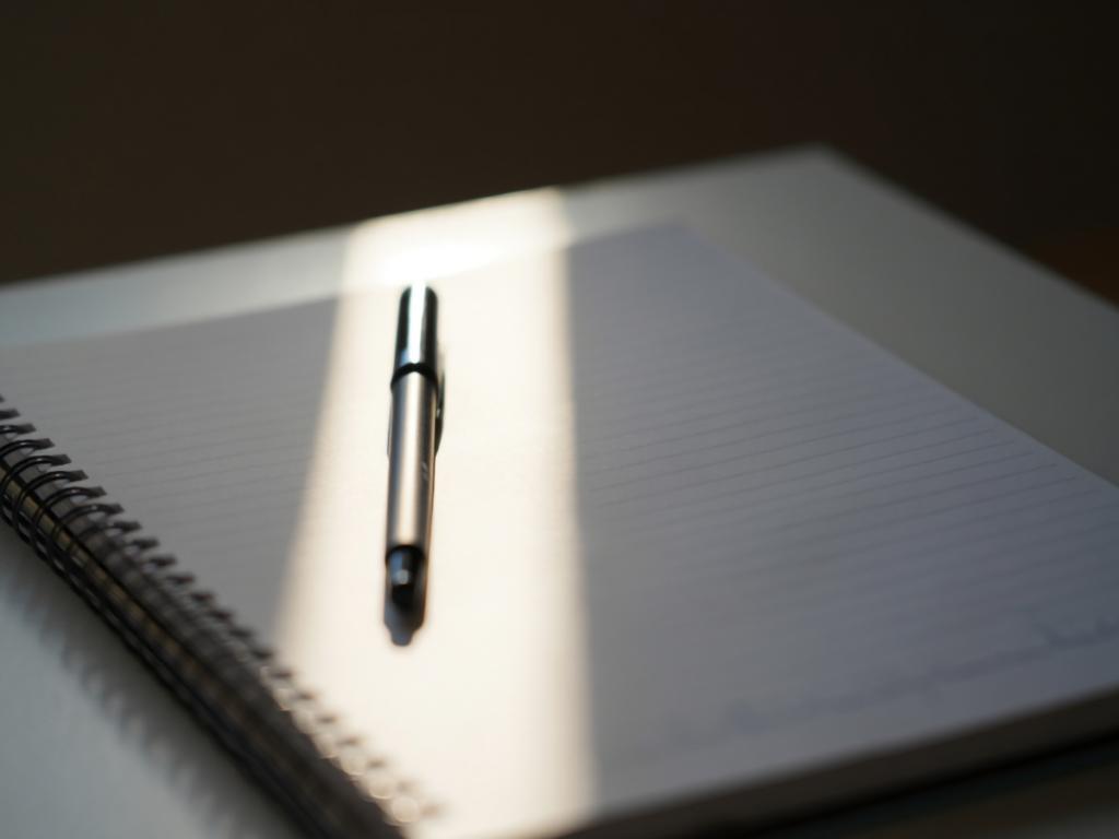 open spiral notebook with pen in natural light